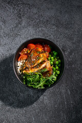 Bowl with chicken meat, rice and beans on a dark background. Eastern cuisine