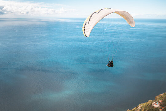 Paragleiter in der Luft &uuml;ber dem blauen Meer