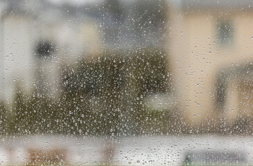 Beautiful blur view of houses through wet window with raindrops. Sweden.