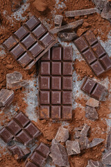 Background Of Chocolate Pieces. Composition of bars and pieces of different dark chocolate, grated cocoa. Chipped Dark Chocolate Pattern.  Top View