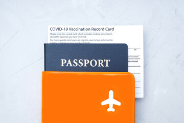 Covid-19 vaccination record card and passport on gray