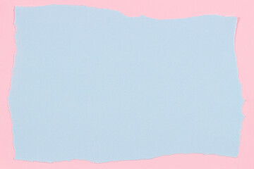 Grunge ripped light blue color paper page with ragged edge on pastel pink paper background. Top view