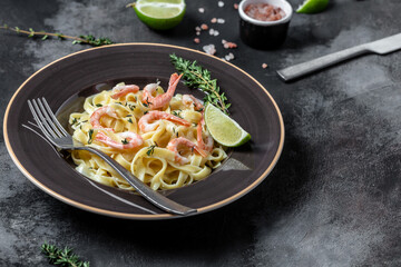 Seafood tagliatelle pasta with grilled shrimps, bechamel sauce and thyme, fettuccine pasta. Italian food. Healthy diet seafood concept. Top view