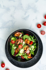 Fresh salad bowl with smoked shrimps, cherry tomatoes, cucumber and mixed leaves, Healthy food. Clean eating. vertical image. top view. place for text