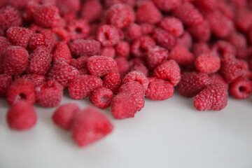 lots of ripe raspberries on a white background, top view