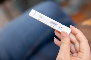 Fototapeta premium Asian Woman Hand with ATK Antigen Test Kit Strip with Positive Result of Covid-19 Virus