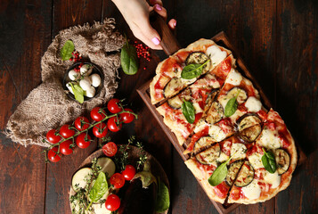 Italian cuisine. Pizza with vegetables and mozzarella. Dough with eggplant, cherry tomatoes, herbs...