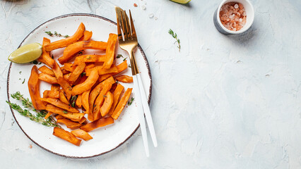 Sweet potato fries with herbs on light background. Long banner format. top view