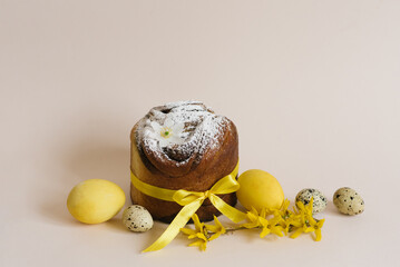 Easter holiday card. Sweet cake with powdered sugar and colored chicken eggs on a light beige background with green branches