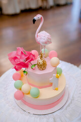 Beautiful cake with pink decor mastic for the birthday of a little girl. Candy bar. Baby birthday theme with flamingo. Festive background decoration with cake and balloons in studio.