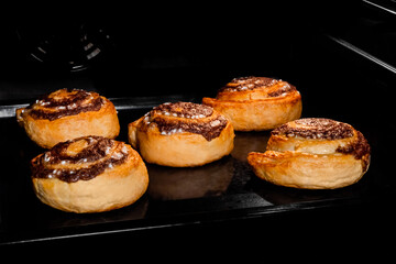 Five baked cinnamon buns on tray in electric oven. Swedish cuisine, homemade bakery, food, cooking and pastry concept