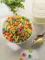 Fruit cereal rings, spoon and milk in a jug on a white background. High angle view. Close-up. The concept is whole grain quick breakfasts. Sweet food, vitamins, carbohydrates, fiber.