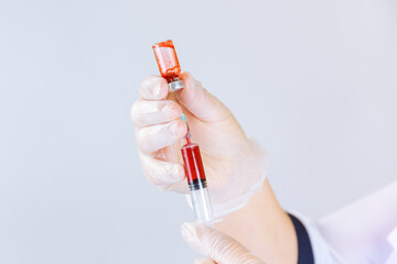 The nurse draws blood into a syringe from a vial for laboratory testing.