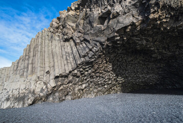 Basalt rock pillars columns at Reynisfjara beach near Vik, South Iceland. Unique geological volcanic formations. Сave at the foot of the Reynisfjall mount.