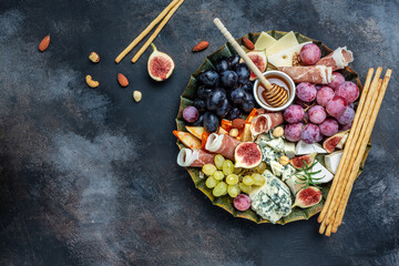 Appetizers table with italian antipasti snacks and wine in glasses. cheese, ham, nuts, fruit, bread sticks. Delicious balanced food concept, Long banner format. top view