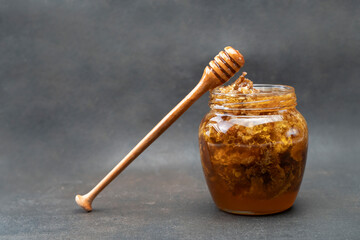 Golden honeycomb and beeswax in a jar of honey on the table. Sweet organic honey in a jar with a...