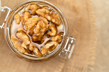 Walnuts in honey close-up. Jar of honey and nuts on a wooden background. Sweet and healthy eating dessert rich in nutrient
