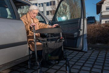 Senior woman with helping rollator getting out of car  - 486774940