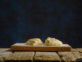 Cooked dough on a wooden table, dark background. Minimalism. There are no people in the photo. There is an empty space to insert. Cooking bread, pizza, pasta.