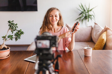 Happy woman blogger or vlogger looking at camera and talking on video shooting