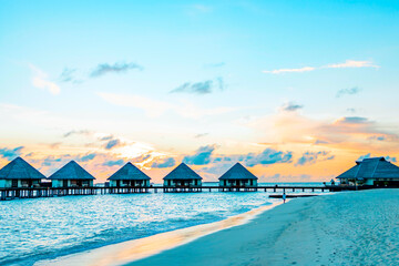 view of the water villas at sunrise in the Maldives, the concept of luxury travel
