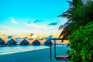 view of the water villas at sunrise in the Maldives, the concept of luxury travel