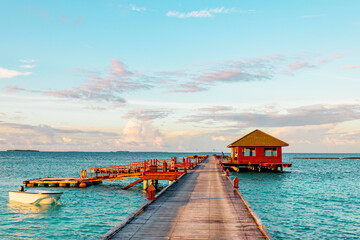 Fototapeta na wymiar wooden pier in the sea at day time with blue sky and beautiful clouds in the Maldives, the concept of luxury travel