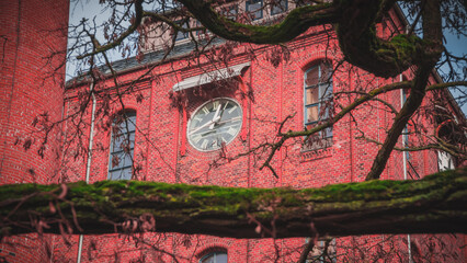 Cultural center Schlachthof Bremen. European industrial brick architecture building. Matte red slaughter house with chimney. Event location. Bicycles and glitterballs in front of tower clock