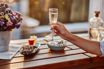 Woman eating fresh oysters and drinking chilled prosecco wine on the summer sunset. Seafood delicacies - 486779165
