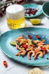 Red boiled shrimps with lime, rosemary, chili on a blue plate on a light background, top view