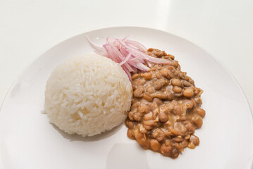 Lentiles portion served with rice and onion salad.