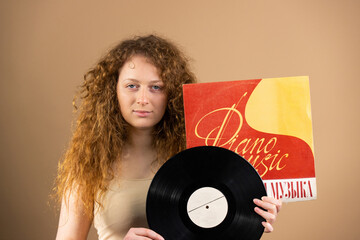 Self-confident redhead woman with blue eyes holding in her hands vinyl record of classical music...
