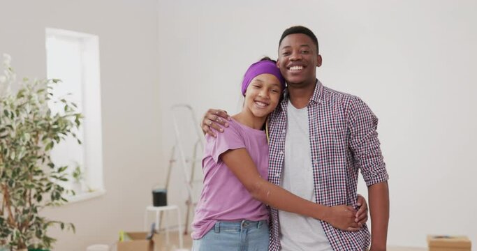 Young man hugs, embraces his younger sister, daughter, together they look into the camera relax after painting walls, renovating a room