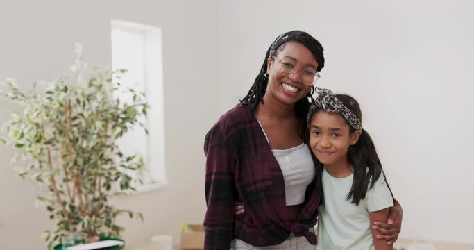 Young woman hugs and embraces her younger sister, daughter, together they look at the camera with smiles, laughing, resting after painting walls, renovating a room