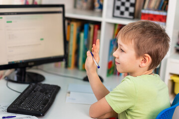 Little young school boy working at home with a laptop and class notes studying in a virtual class. Distance education and learning, e-learning, online learning concept