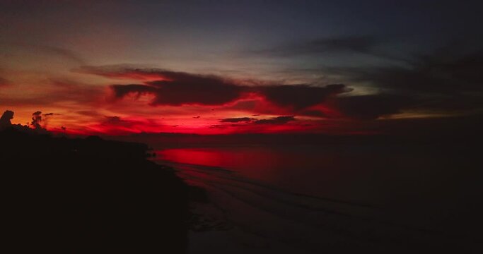 Unusual dark red sunset or dawn of sun over ocean, illuminates twilight. Summer landscape, concept