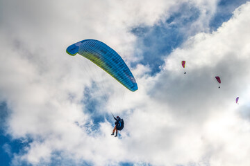 People try paragliding flying with parachutes against clouds