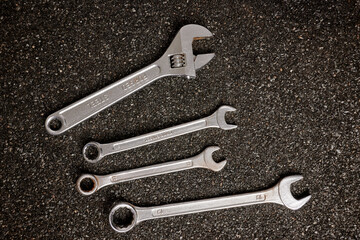 Metal wrenches on ruberoid mineral surface. Set of steel spanner tools. Workshop equipment for mechanics repair. Iron service toolkit. Setup wrenches made of chromed steel. Dark asphalted background.