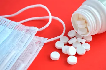 Fotobehang White pills and medical extras on a red background © Anastasiya