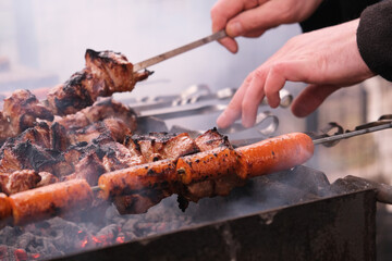 
a man roasts meat on a fire.
Close-up of hands and shish kebab.
Cooking pork neck on the grill....