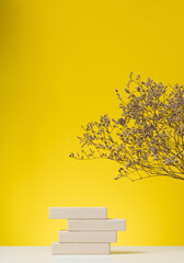 wooden podium to showcase cosmetics and other items, yellow background with dry wildflowers and...