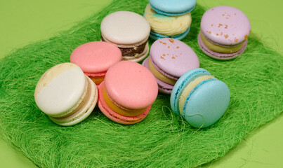 baked macarons with different flavors on a green background, top view