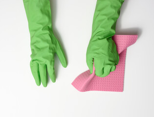 hand in a green rubber glove holds a soft sponge for cleaning surfaces on a white background