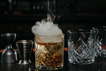 cocktail with smoke and bartender equipment on a dark background in a bar