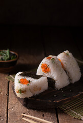 Japanese traditional snack rice balls triangle onigiri with raw salmon and red caviar on a dark...