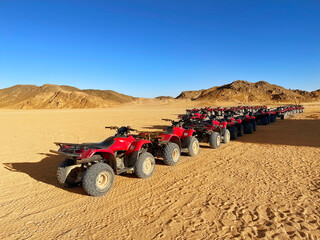 Many red quad bikes are standing in the desert without people. Quad parking - Powered by Adobe