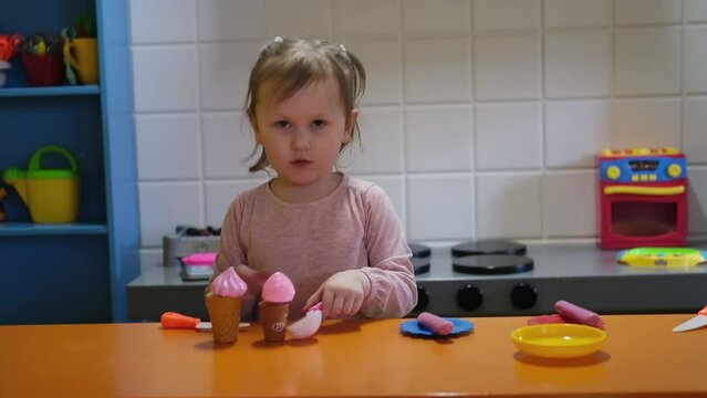 Happy preschool girl playing with toy kitchen at kids game center. Fun in kids room.