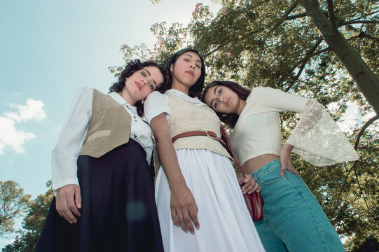 Low angle view of three girls in a square looking at the camera with the sun behind them.