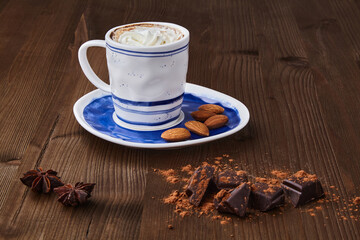 Cup of cappuccino, chopped chocolate, spices and almonds