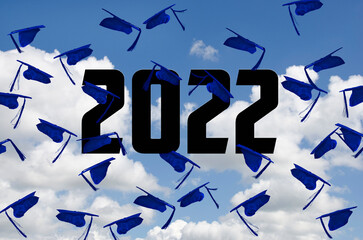 Blue graduation caps airborne in summer sky with 2022 text